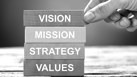 Closeup of hand building colorful blocks of vision mission strategy and values on wood_edi