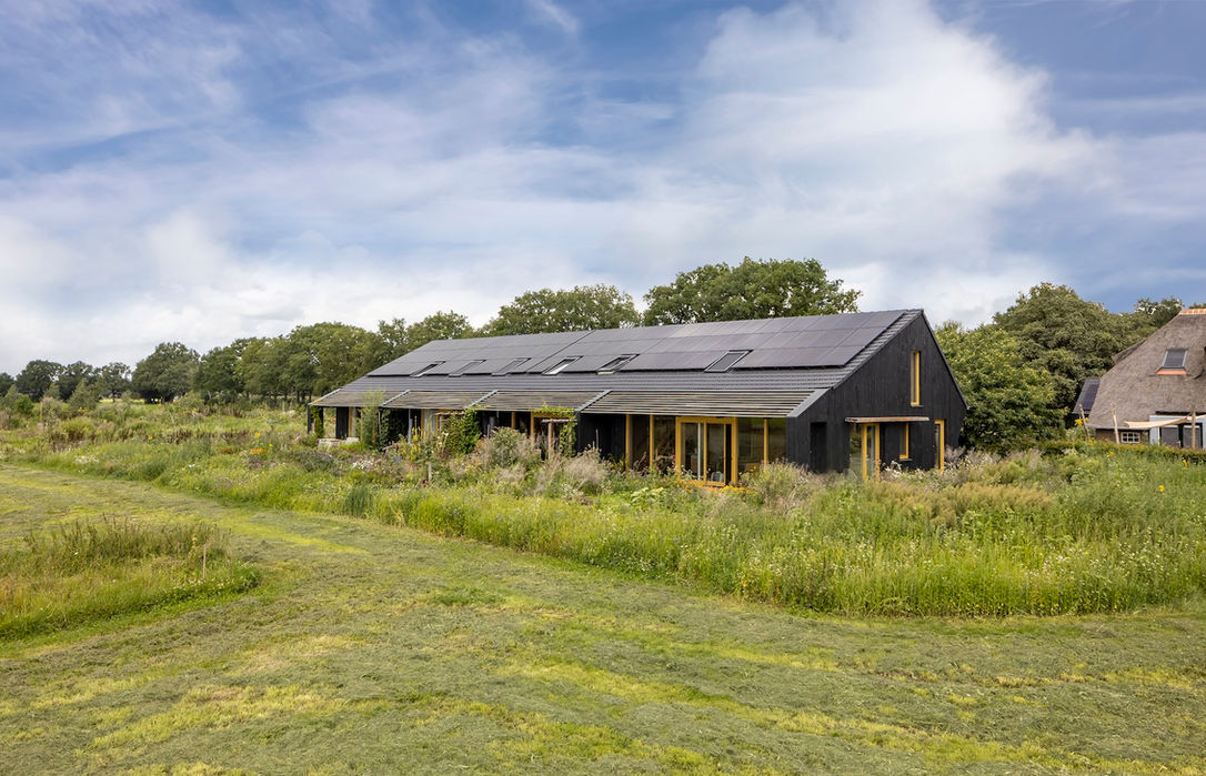 Ecologische schuurwoning met houten gevel en zonnepanelen op dak
