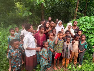 A large group of rescued Nigerian schoolchildren and their teachers standing together in thick green forest vegetation shortly after their release from captivity.