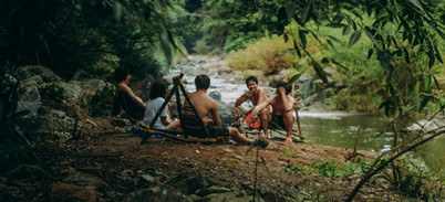 Adventurers gathering beside a rocky creek beneath dense Khao Sok vegetation