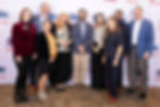 Group of nine people smiling in front of a backdrop with "ABC West Tennessee." They wear formal attire; background has logos and text.