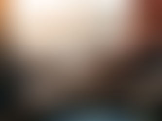 Two people are sitting closely, holding hands in a comforting manner. One wears an orange shirt, with soft sunlight in the background.