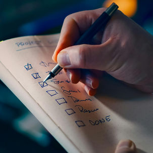 The right hand of a person checking off a checklist book with a fountain pen.