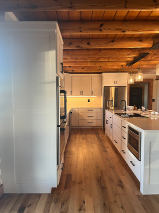 Custom kitchen with white cabinets, wood ceiling, and hardwood floors