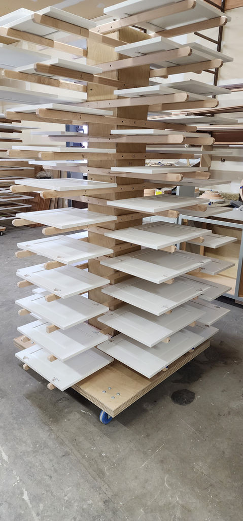 Cabinet doors stacked on drying rack during finishing process