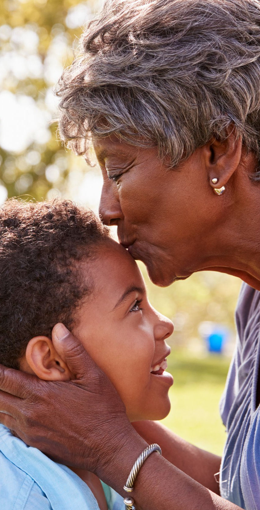 Grandmother embracing granddaughter in a UK park, symbolising Nigerian family visiting for medical treatment