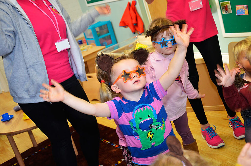 Happy children at What A Hoot Nursery singing and dancing with teachers