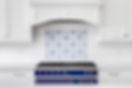 A kitchen detail with a blue and stainless steel stove, subway and mosaic tiled backsplash