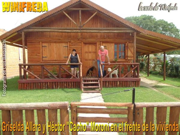 Griselda Allara y Héctor "Cacho" Moroni con sus mascotas en el frente de la vivienda de madera