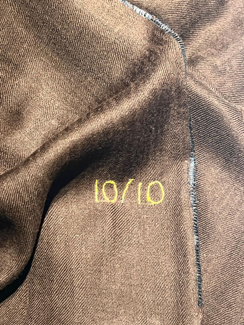 Braunes Stoffstück mit gelbem 10/10-Text, Detailaufnahme, Textil, Nahaufnahme, Muster.