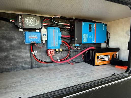 typical rv electrical system setup inside a storage compartment in a luxury motorhome and fifth wheel. you can see lots of different wires and electrical componets.