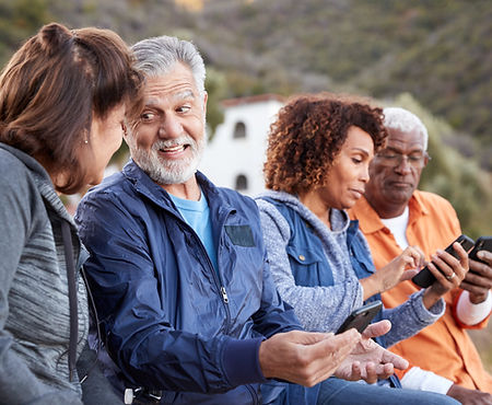 Diverse group of seniors using smartphones outdoors.