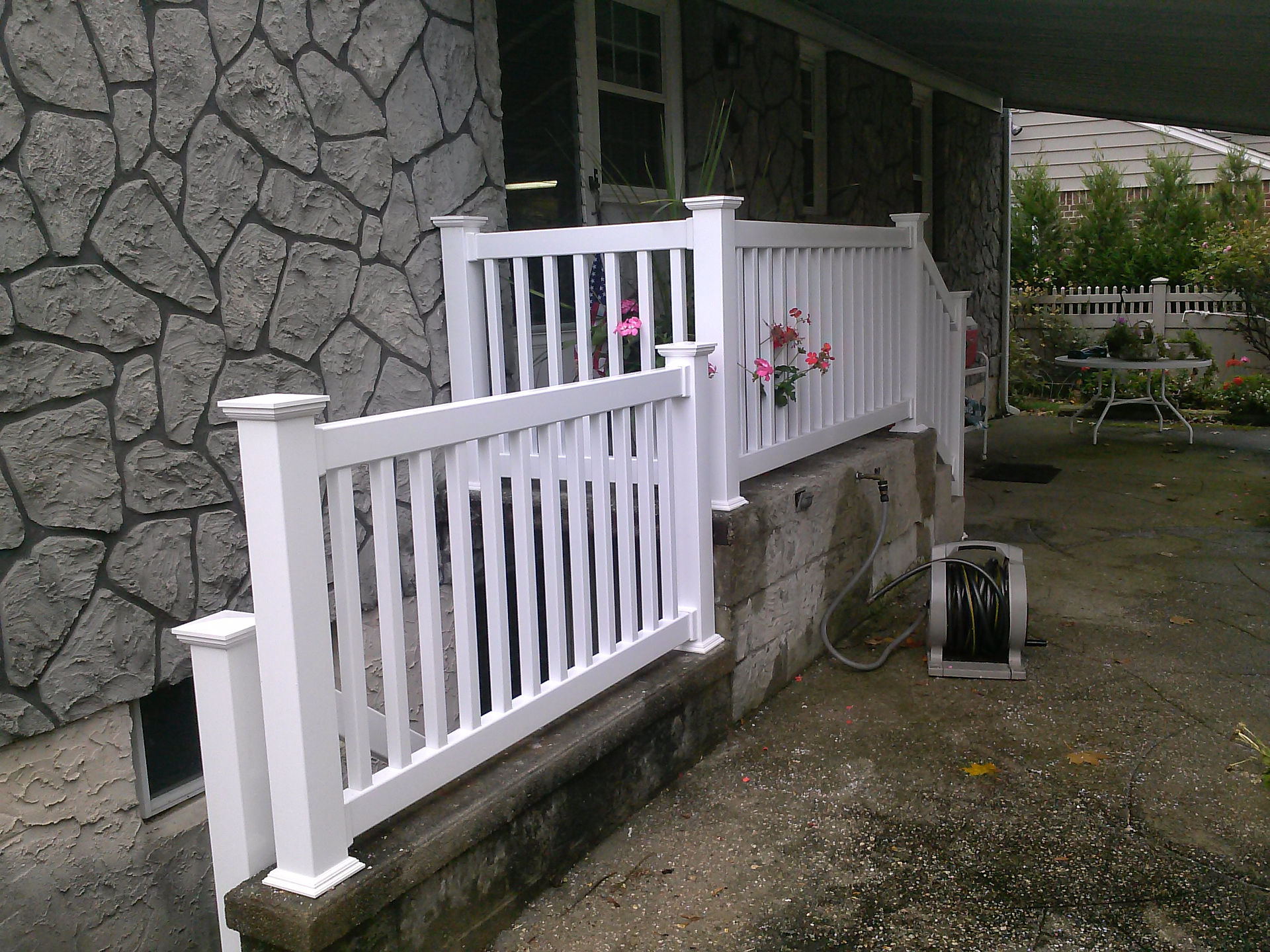 White vinyl fence on a house with flowers and stone walls North Shore Fence Co