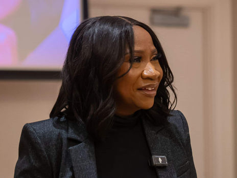 Adissa Barry addresses a crowd, wearing a black blazer. Speaking at an event.