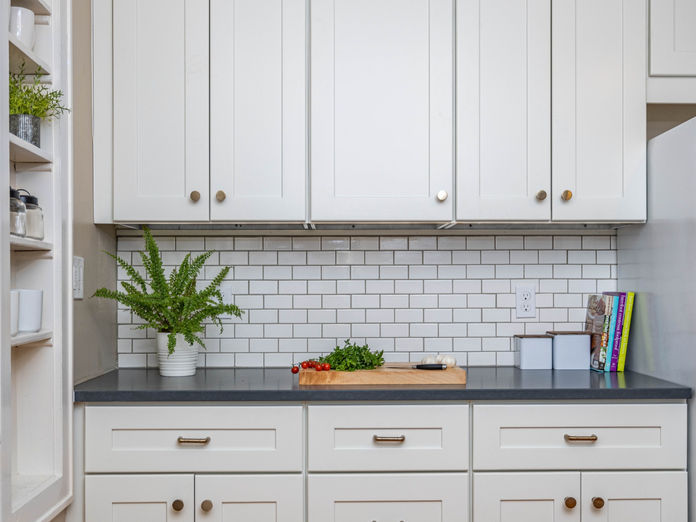 Timeless kitchen refresh with crisp white cabinetry, subway tile backsplash, and sleek dark countertops. Fresh greenery and open shelving add modern function to a classic design.