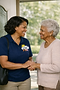 Caregiver smiling and holding hands with an elderly woman.