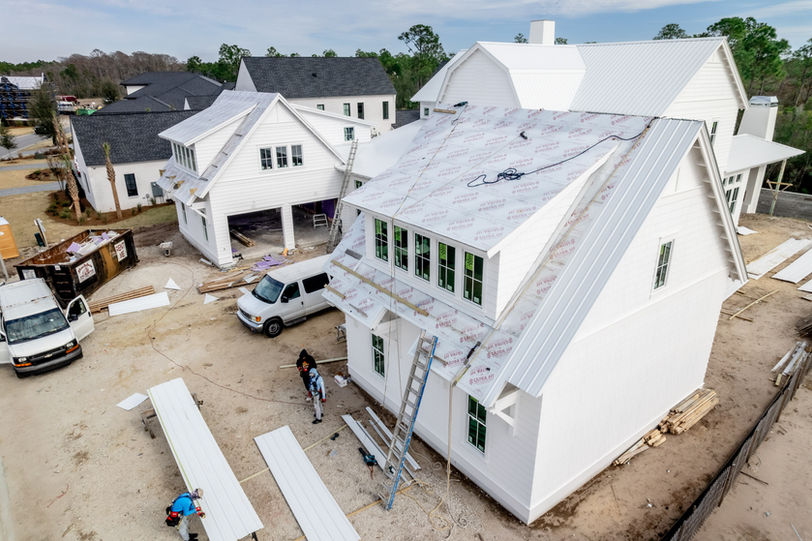 A large white house being built with a luxury metal roof and design