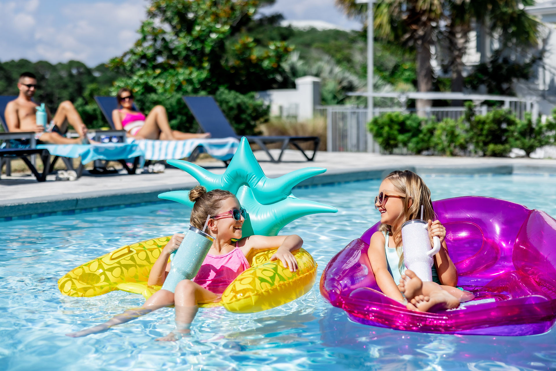 two girls in pool talking with tumblers