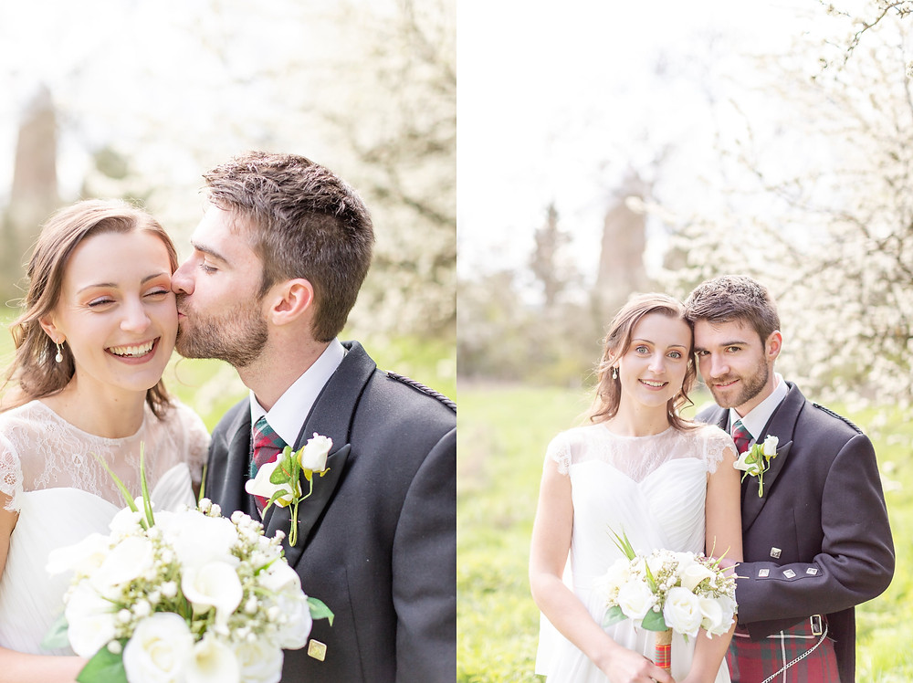 bride and groom smile at the camera, groom kisses bride on the cheek during portraits with Sam and Jenna Photography, Devon wedding photographer