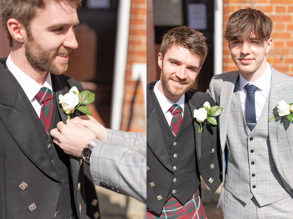 someone is straightening the groom's boutonniere, groom and best man smile at the camera before the wedding ceremony
