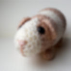 crochet guinea pig made with light brown and cream yarn, safety eyes and an embroidered nose