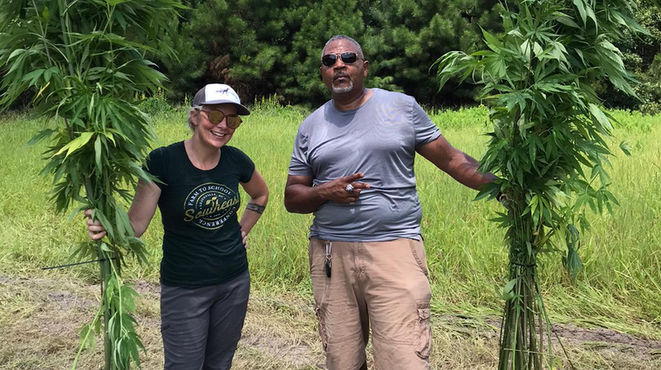 Kelly from Clemson and Derick CEO of Bossville holding up hemp stalks