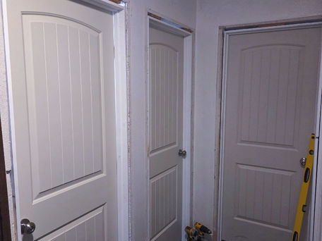 Three newly hung interior doors in a hallway during a replacement project, shown before final trim is installed.
