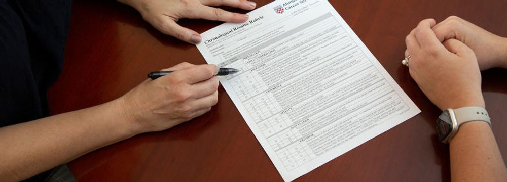 Overhead view of the hands of two people reviewing a CV