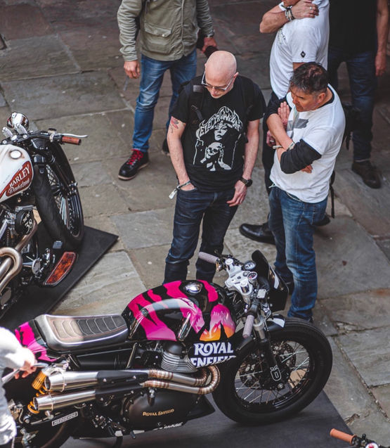 Vue de haut de deux personne regardant la savage personnalisée par Hedgehog Motocycles lors d'une exposition 