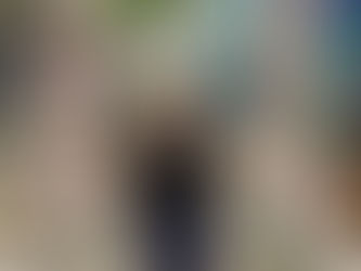 Woman smiling on a macramé swing adorned with pink flowers, set against a tropical beach mural backdrop with palm trees and blue sea.