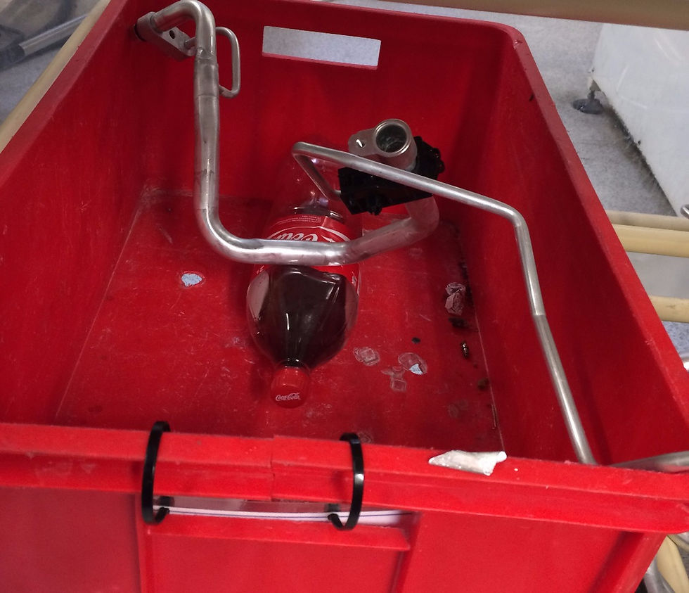 A defect part in a red bin in a factory with some rubbish in the bin