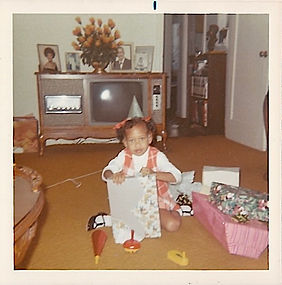 Little girl poses and opens gifts in the TV space, circa 1963-67.