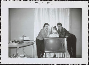 Couple pose with TV between them, ship-shaped TV lamp-clock on top, 1958.