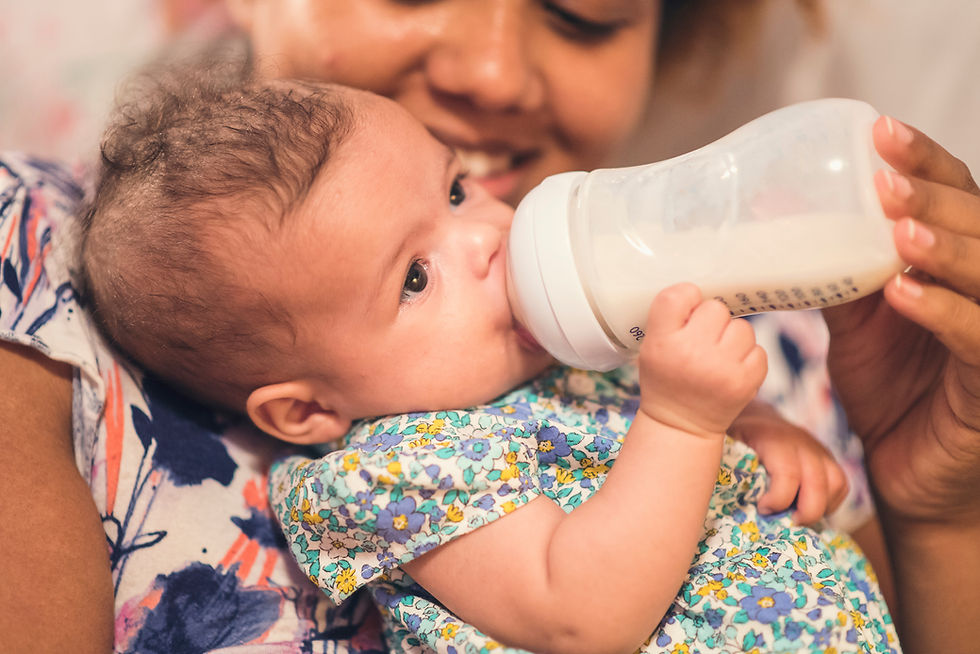 Smiling mother feeds newborn baby with a bottle