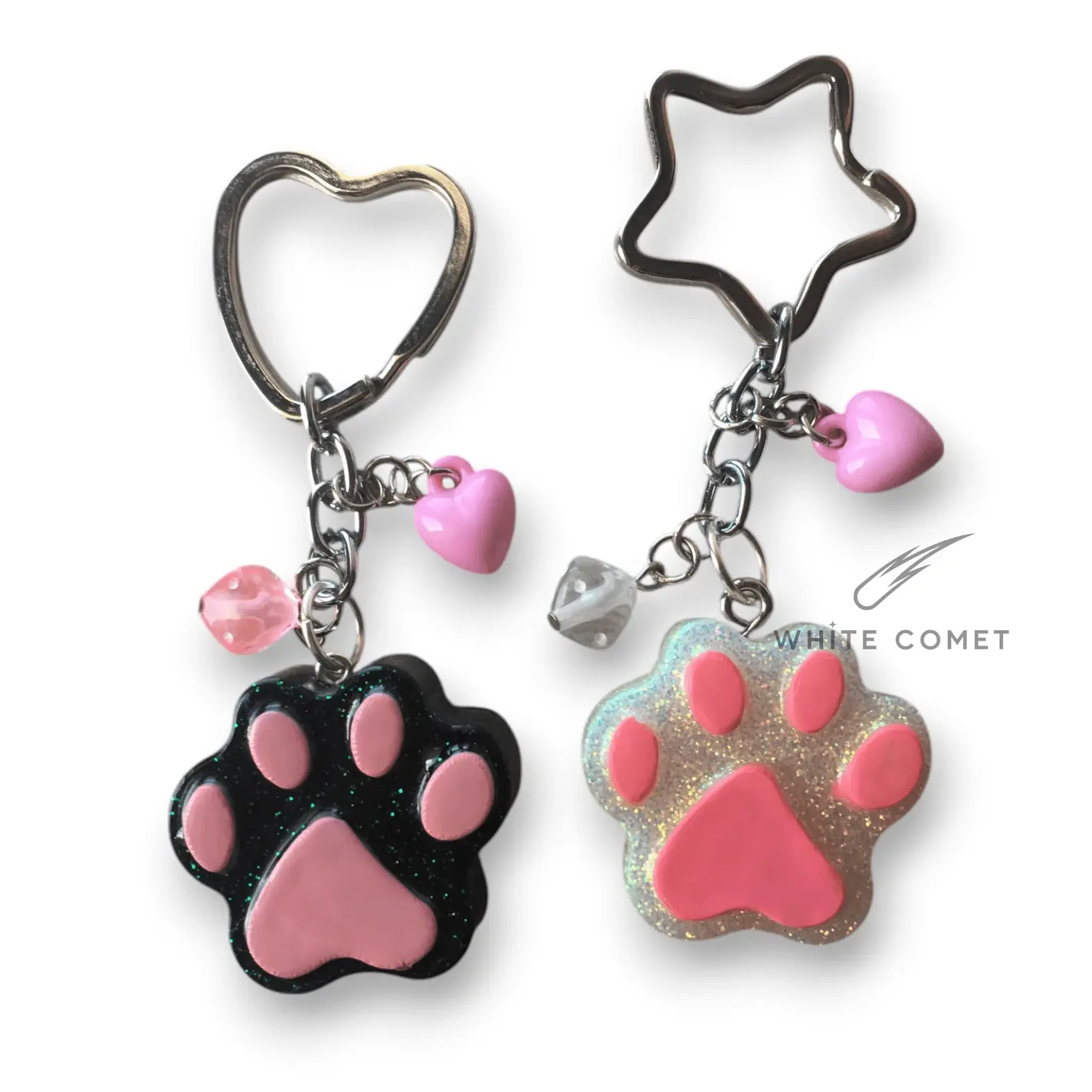 Due portachiavi con zampette in resina, colorate glitterate, con mini charm appesi. Anello a cuore o stella