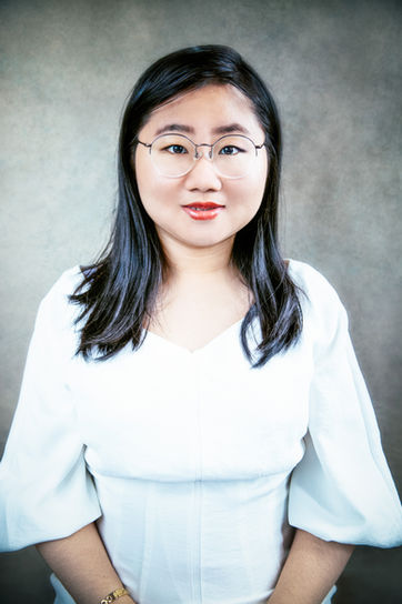 women with glasses and white dress headshot.