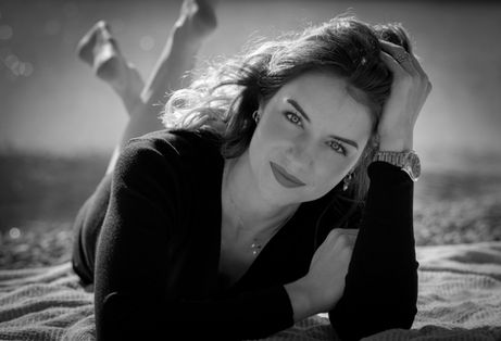 Femme allongée sur une plage, regardant l'appareil photo à Narbonne, NR PHOTOGRAPHIES.