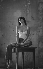 Femme assise, regardant pensivement, dans un bâtiment industriel. NR PHOTOGRAPHIES.
