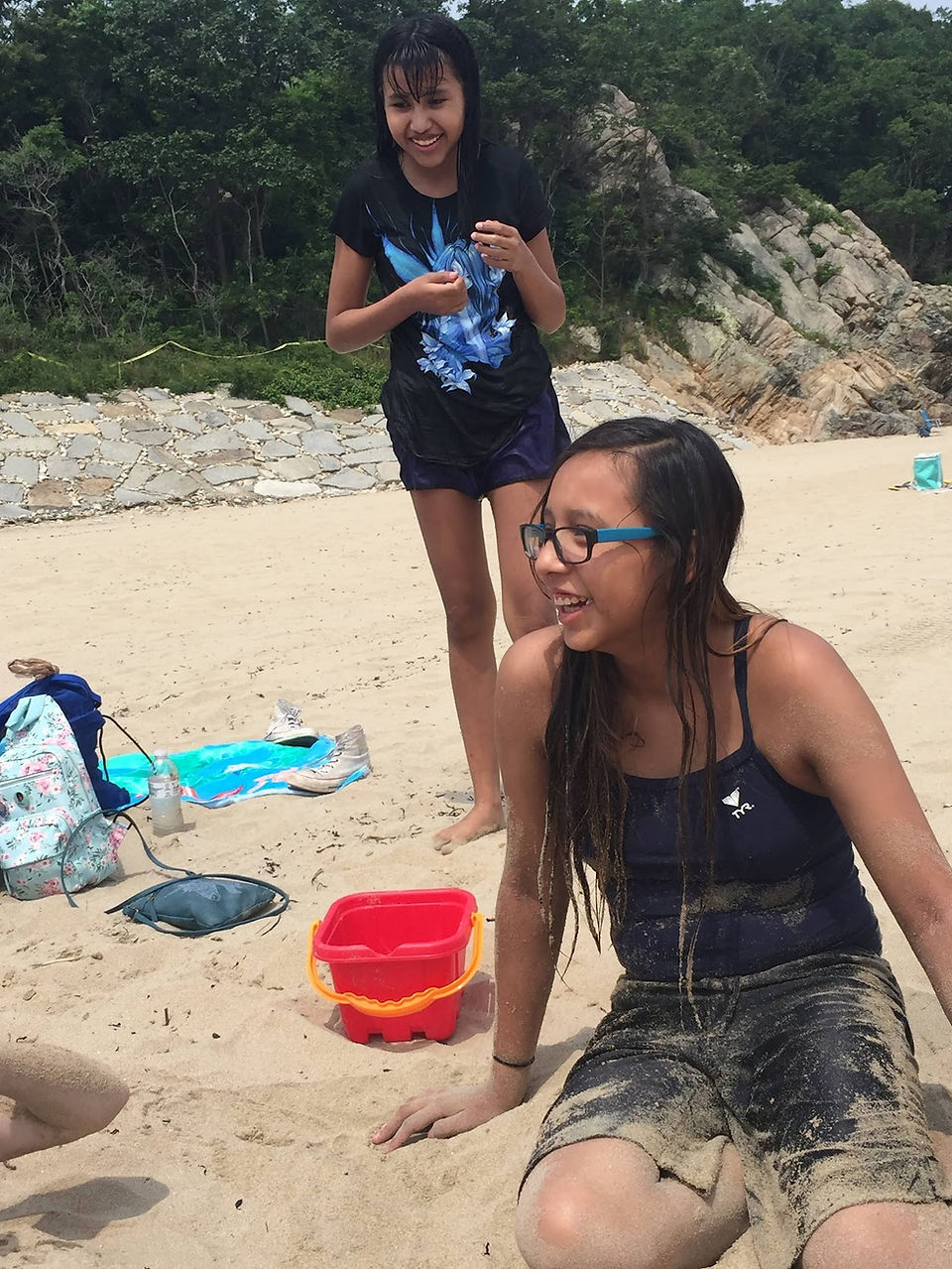 Young Lakota girl sitting on the beach smiling and having fun