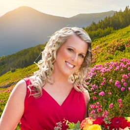 Tiffany Fehribach, Travel Designer Romantics Travel team member standing in a mountain meadow filled with colorful flowers