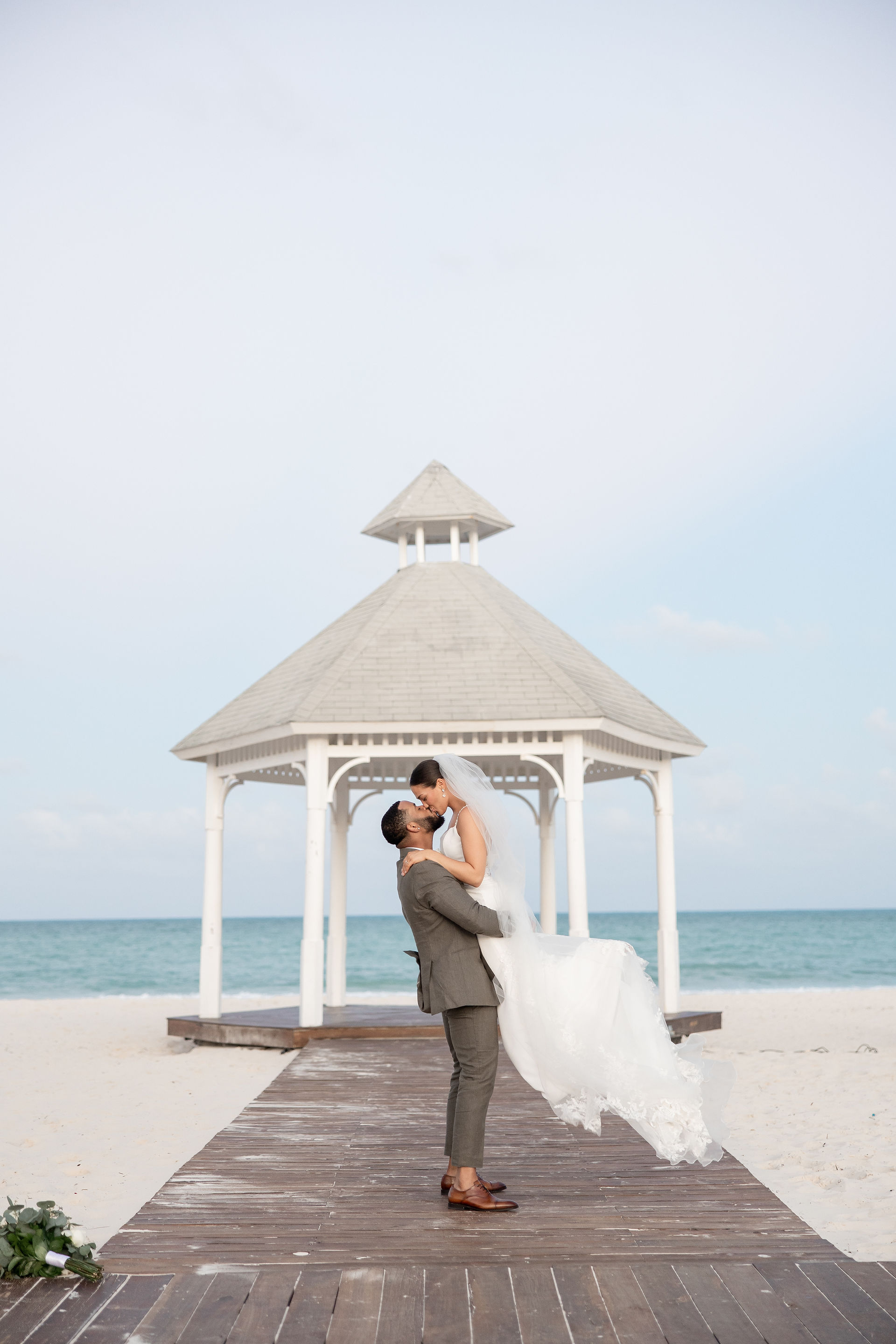 wedding couple kissing by the beach gazebo