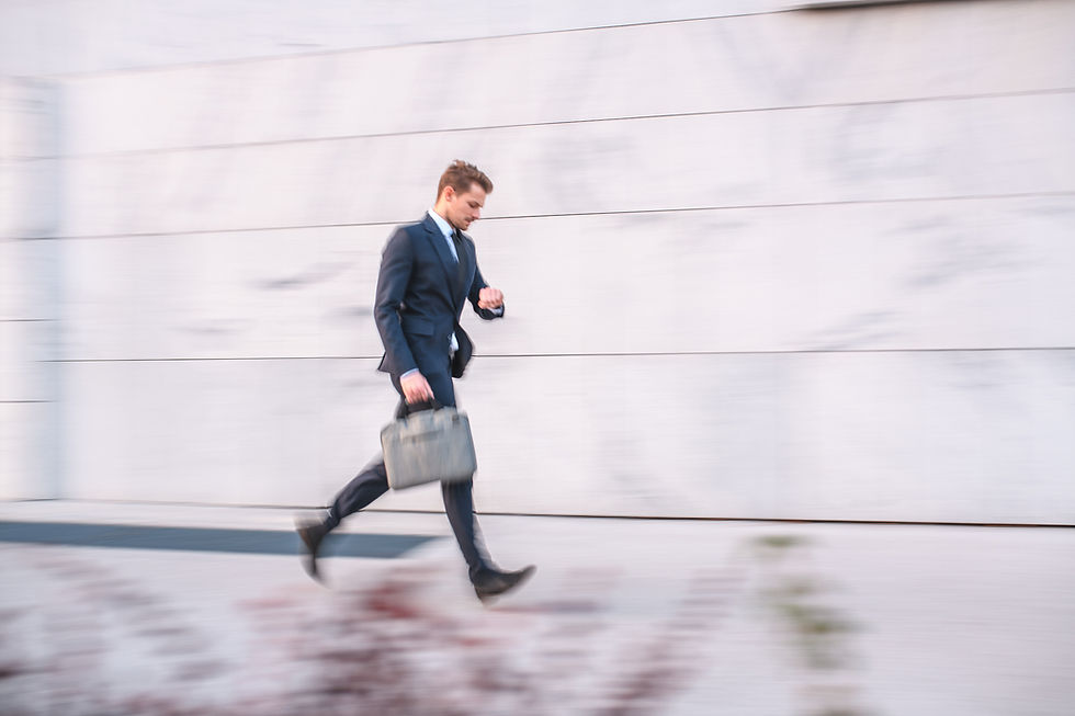 Blurry photo of man rushing to work with laptop bag in hand, checking his watch.