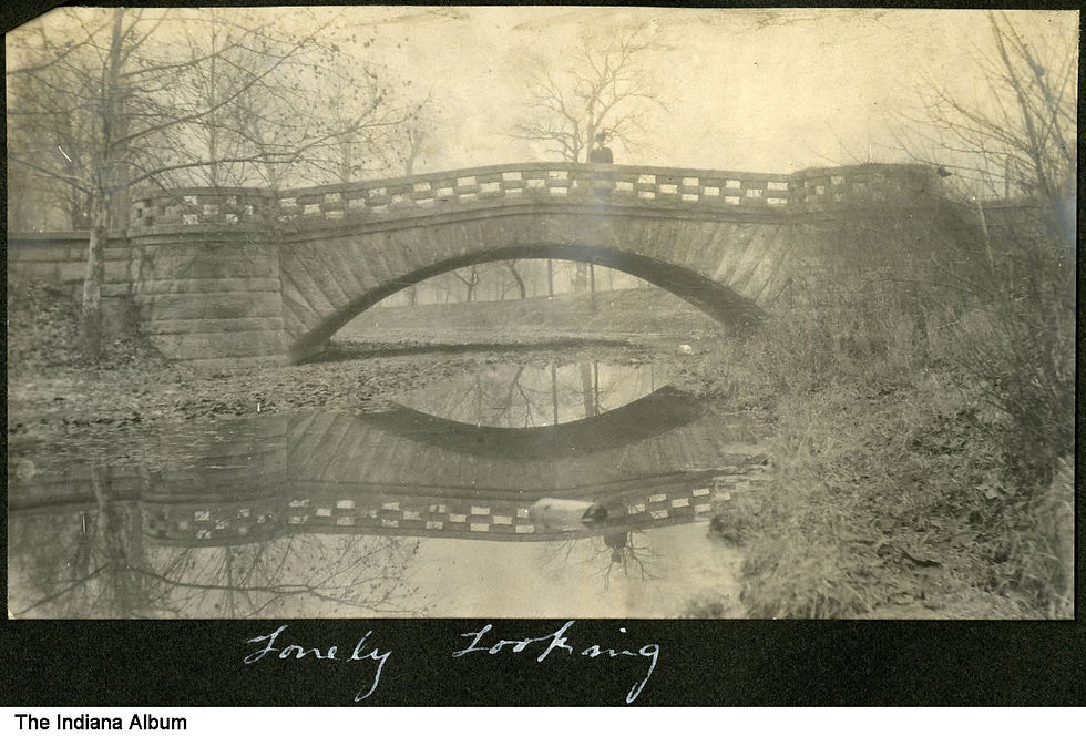 Stone bridge over a reflective stream in a foggy, barren landscape. Two people stand on the bridge. Text reads: "Lovely Looking."