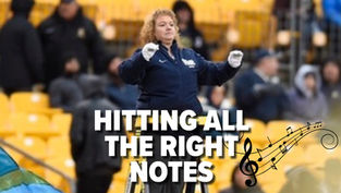 Virginia Schaap, assistant band director, conducting from a ladder in a stadium with overlaid title text "Hitting All the Right Notes" and musical notes graphic.