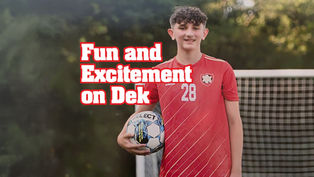 Graphic feature image showcasing Dominic Porter in a red athletic jersey with the number 28, holding a soccer ball under his right arm in front of a goal net. The bold text "Fun and Excitement on Dek" is overlaid in white with a thick red outline on the left side of the frame against a blurred green background.