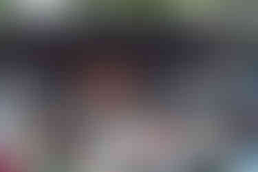 A band performs on the Rotary Amphitheater stage to an audience seated in lawn chairs and at picnic tables on a grassy field.