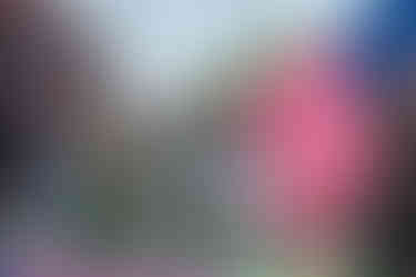 A group of men in military camouflage stand on a parade float and salute as a large American flag waves behind them.