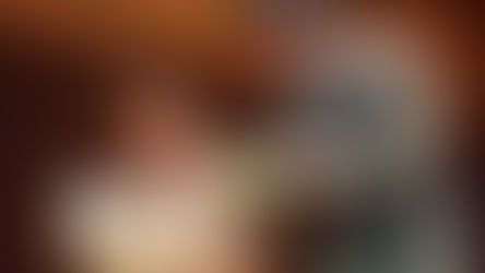 Dorothy Gale and Professor Marvel share a scene on stage, both gazing into a glowing crystal ball positioned between them. Dorothy, wearing her blue gingham dress, sits and holds the prop with both hands. Professor Marvel, wearing his gray suit and a new dark turban, stands over her and gestures toward the crystal ball with both hands.