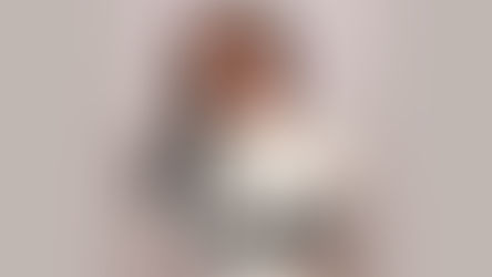 A professional portrait of Alicia Tavani, world champion martial artist and "Squid Game: The Challenge" contestant. She is smiling warmly and wearing a white turtleneck sweater.