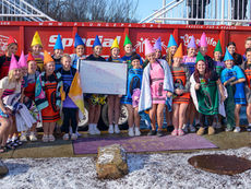 A large group of Plum Senior High School students and staff, some in costumes, standing together in front of a portable pool during the Special Olympics Polar Plunge fundraiser.